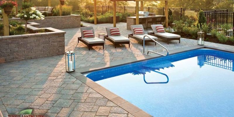 A patio with a swimming pool and lounge chairs.